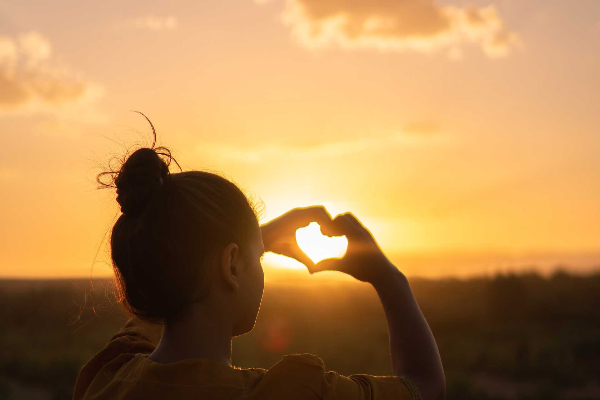 sunset and a hand making a heart