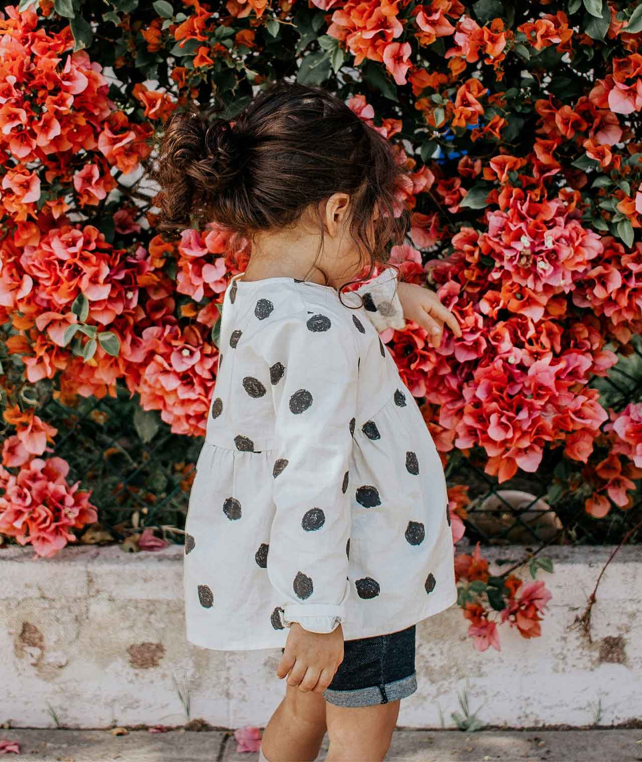 young girl by a wall of roses